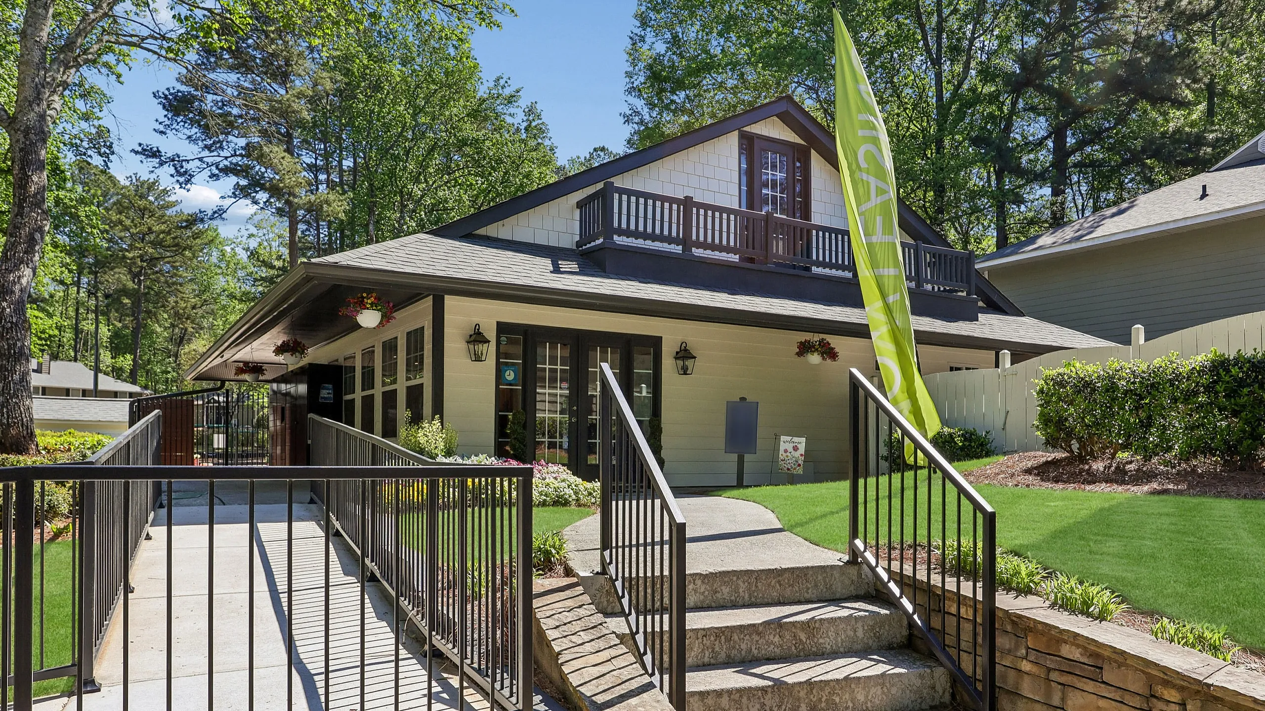 Charming clubhouse exterior with lush greenery, inviting entrance, and picturesque setting.