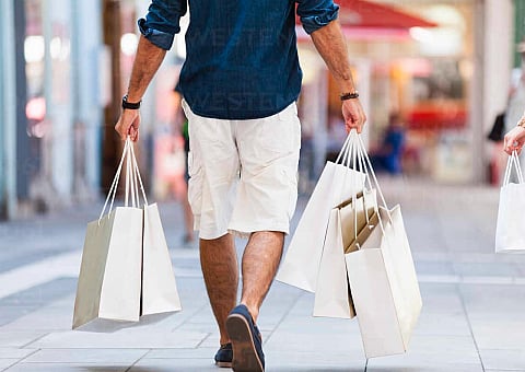 Vibrant shopping scene featuring two people walking with numerous shopping bags in a stylish outdoor setting.