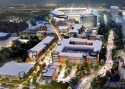 Vibrant aerial view of a modern urban development, featuring illuminated streets, contemporary architecture, and a bustling stadium nearby, creating a lively and inviting atmosphere.