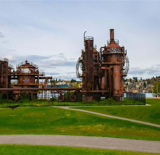 An old, rusted industrial structure sits in a grassy field.