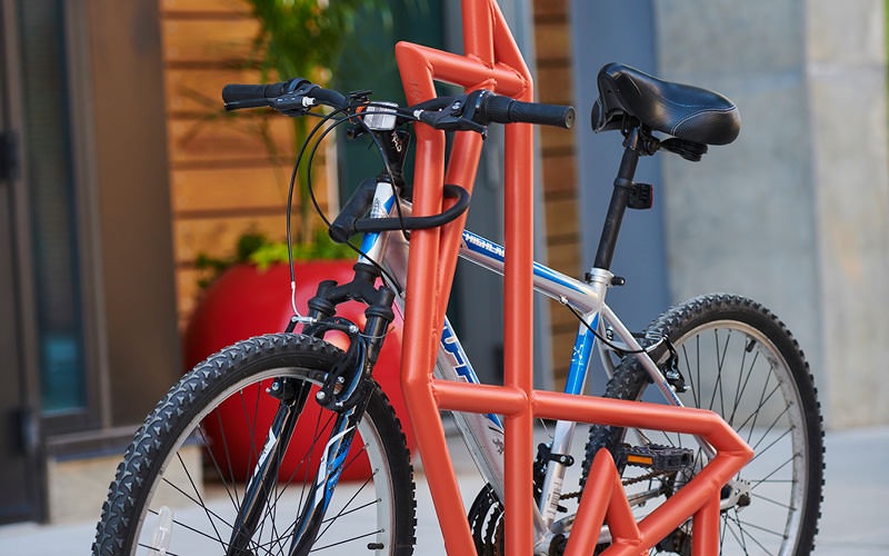 bicycle secured to rack on sidewalk