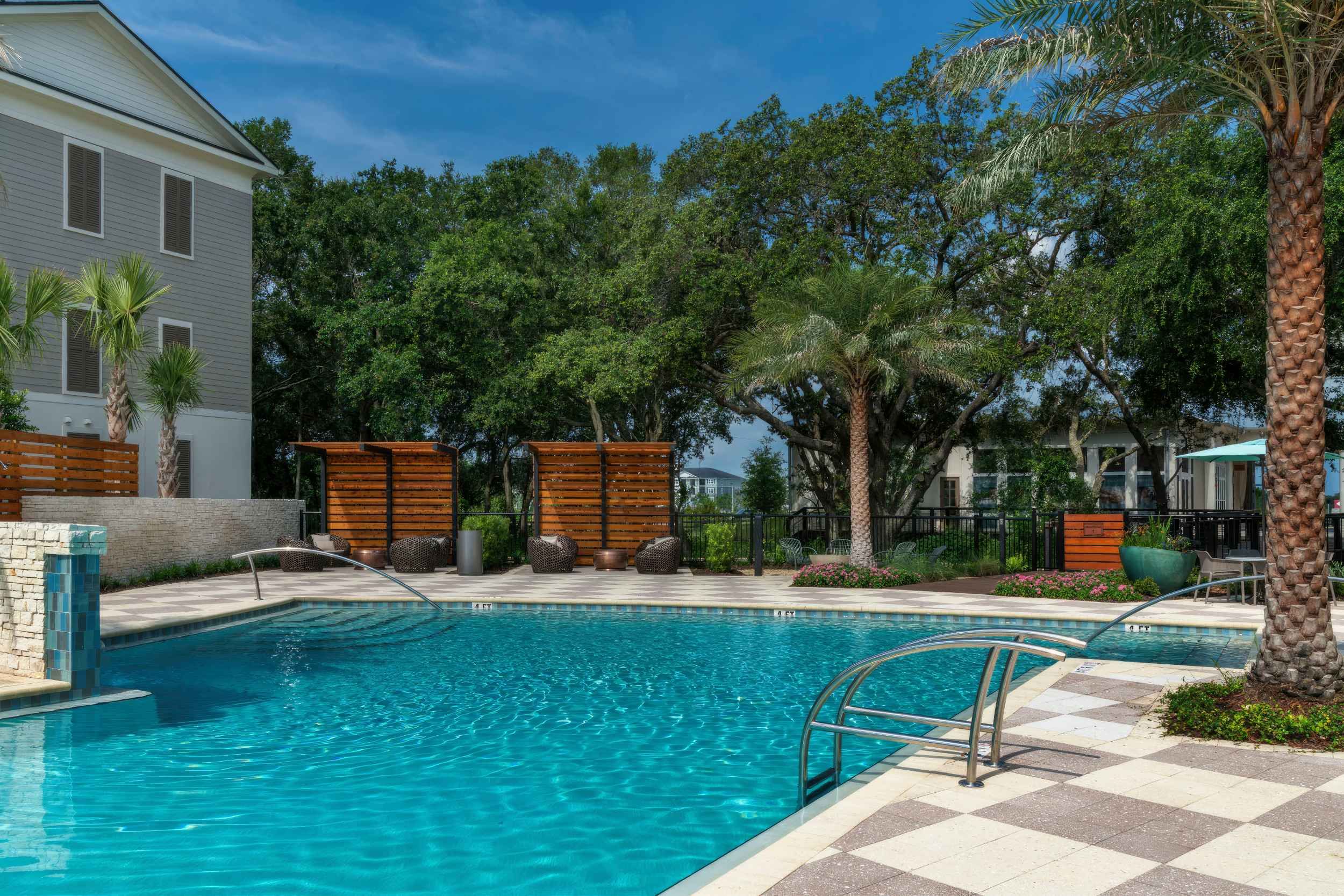 A serene pool surrounded by trees and lounge areas, perfect for relaxation.