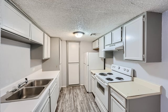 Kitchen with white cabinets, white countertops, a double sink, a white stove, and a white refrigerator.