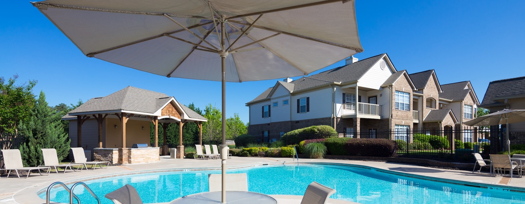 a swimming pool with a table, chairs and an umbrella