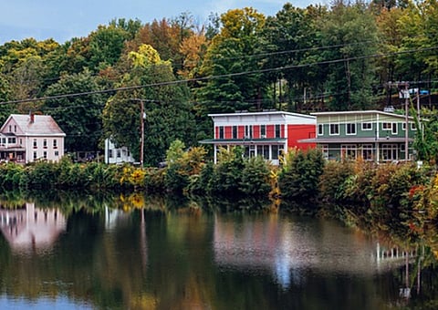 Charming lakeside view showcasing colorful houses surrounded by lush greenery, offering a serene and picturesque living environment.