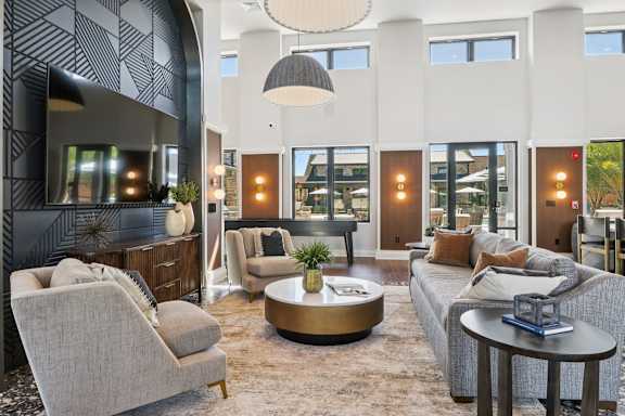 A modern living room with a grey sofa, a grey armchair, a coffee table, and a fireplace.at The Liliana Apartment Homes, Pooler, GA 31322