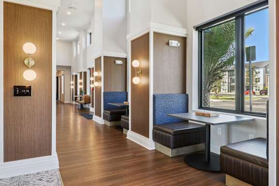 A hallway with brown wood floors and a bench with a blue cushion.at The Liliana Apartment Homes, Pooler, GA 31322