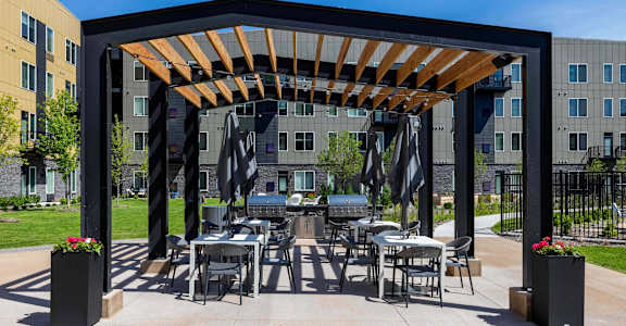 A patio with a table and chairs under a wooden pergola.