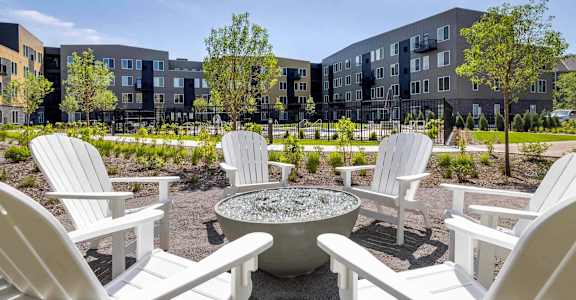 A white Adirondack chair is in front of a grey building.
