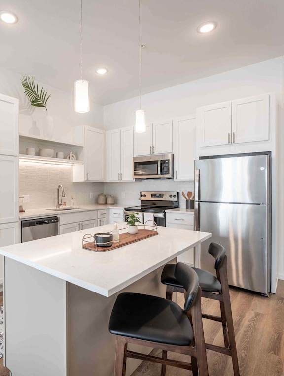 A kitchen with a white table and black chairs.