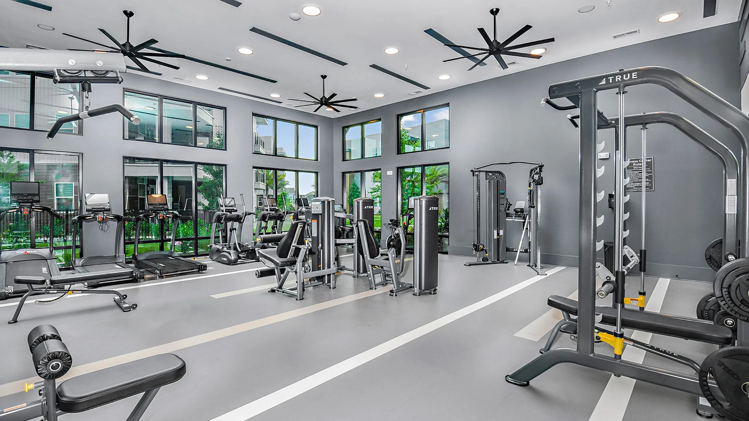 Spacious and modern fitness center with high ceilings, state-of-the-art equipment, and large windows offering scenic views.