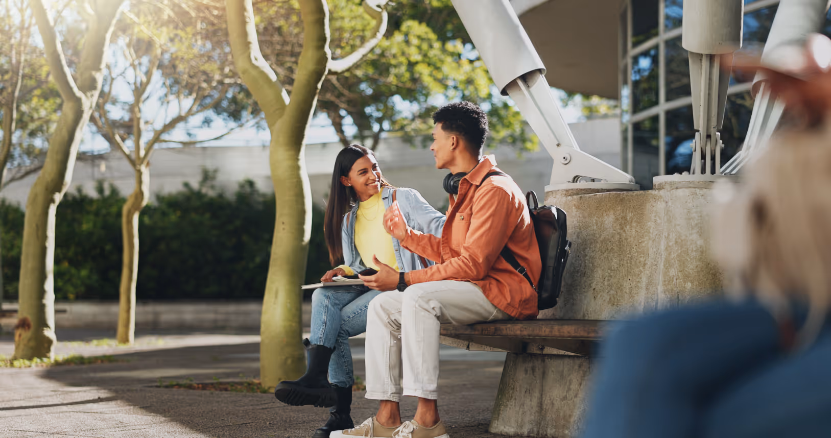 Students sitting on bench outdoors chatting stock image