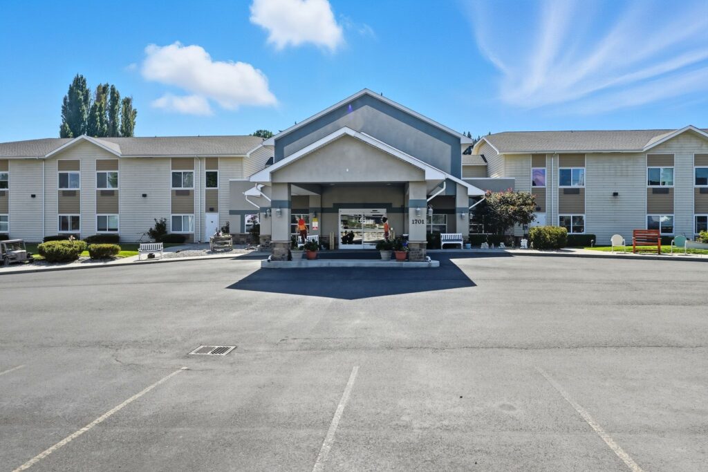Bright, welcoming entrance of a retirement home with landscaped gardens and benches for relaxation.