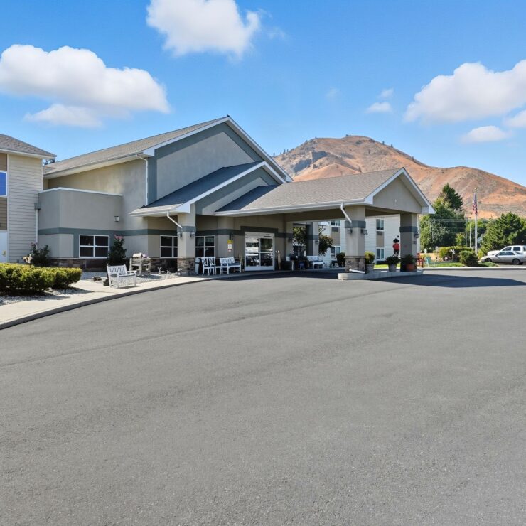 Peaceful retirement home entrance with seating areas and mountain views under a bright sky