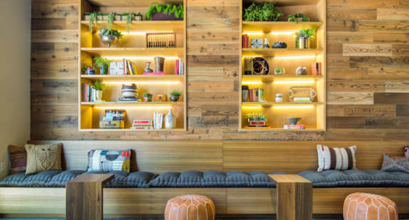 A room with a couch, a table, and a shelf with plants and decorative items.