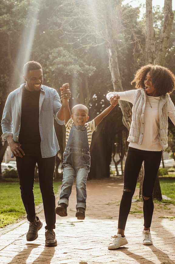 A family of three is walking in a park at Highland Ridge Apartments, Capitol Heights