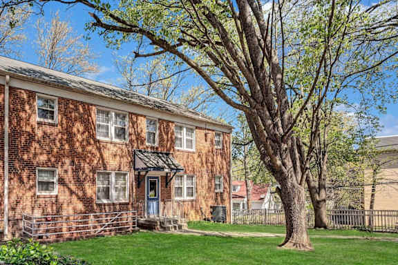 A red brick building with a tree in front at Highland Ridge Apartments, Capitol Heights