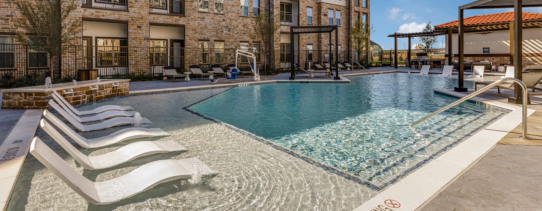 Three-Bedroom Apartments in Grand Prairie, TX -Aven at the Cove - Resort-Style Pool with a Sundeck, Cabanas, Lounge Chairs, and a Water Fountain