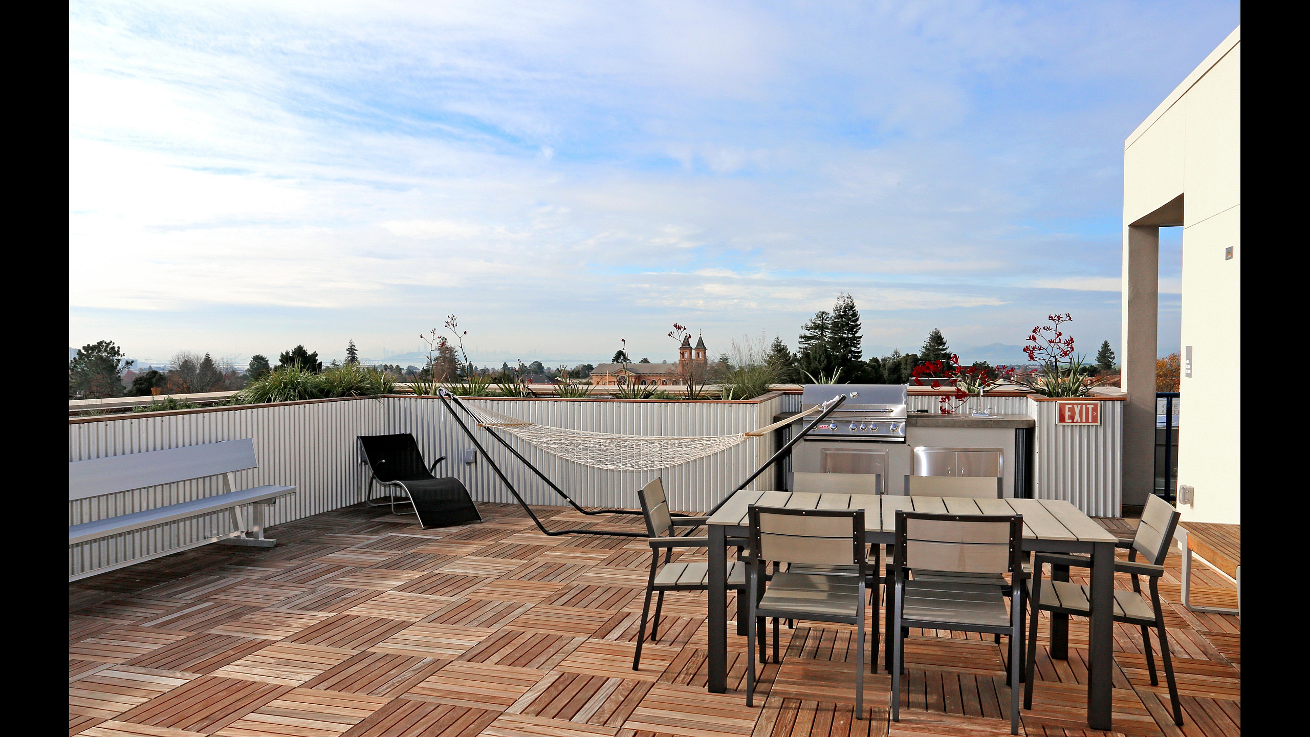 Charming rooftop terrace with modern outdoor furniture, a hammock, and a sleek barbecue grill offering scenic views.