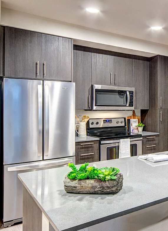 A modern kitchen with a refrigerator, microwave, oven, sink, and a countertop at Upton Flats, Seattle, WA, 98126