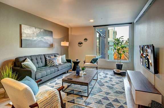 A living room with a grey couch, a coffee table, a chair, and a painting on the wall.