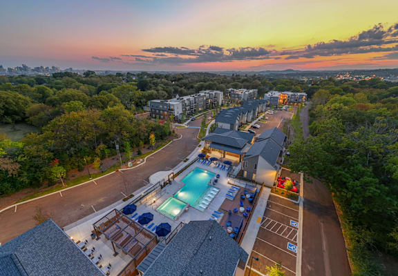A sunset view of a resort with a pool and a parking lot.