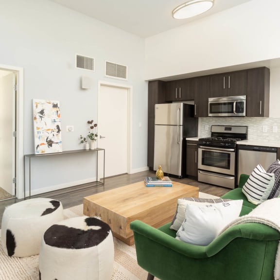 a living area with a couch coffee table and a kitchen in the background