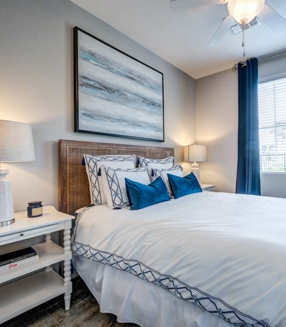 Bedroom with blue accent pillows and curtains at Vistoria On Camelback Apartments, Litchfield Park, AZ 85340
