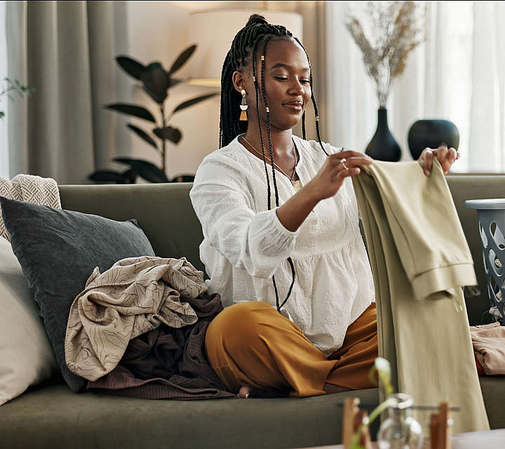 Cozy apartment living room with soft lighting, a stylish green sofa, and a woman folding clothes, creating a warm and inviting atmosphere.