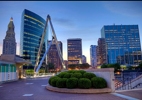 Stunning cityscape at dusk featuring modern glass skyscrapers and a unique architectural sculpture framed by vibrant evening lights.