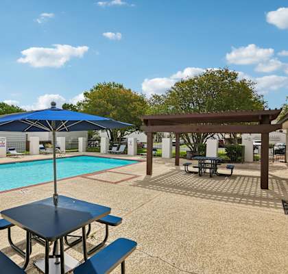 A pool with a table and chairs and an umbrella.
