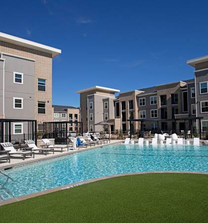 A large swimming pool in front of apartment buildings.