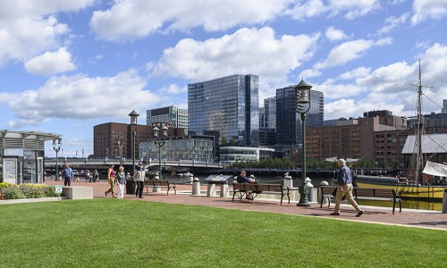 grassy area at Atlantic Wharf Waterfront with people walking around or sitting on benches overlooking the river
