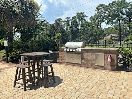 A patio with a table and chairs and a grill.