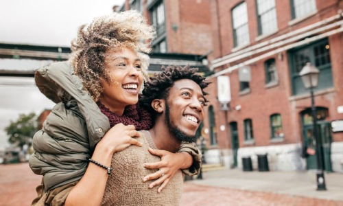 Man and woman walking along a neighborhood street and smiling.
