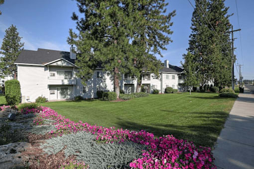 A white house with a grey roof and a green lawn in front.