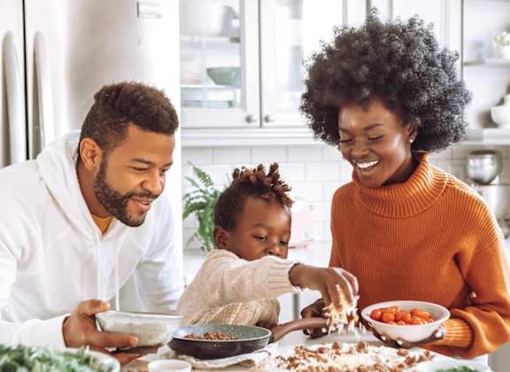 A family of three is having a meal together in a brightly lit kitchen.