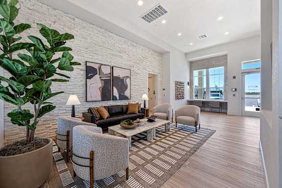 A living room with a couch, chairs, and a potted plant.