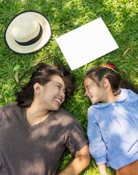 A group of friends are hugging and laughing together in a sunny outdoor setting.