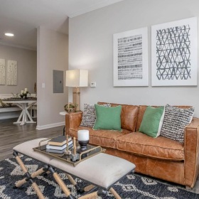 An interior view of a living room with a couch, a coffee table, and a side table with a lamp at The Summit on 401 apartments in Fayetteville, NC.