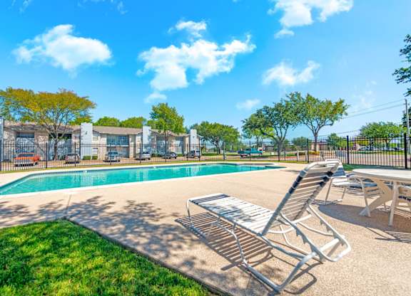 Swimming pool with lounge chairs and mature trees at Marshall Apartments, Texas