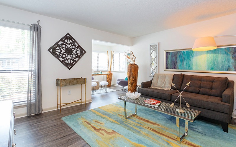 Spacious and well lit living room with wood floors and an open floor plan with access to the kitchen.