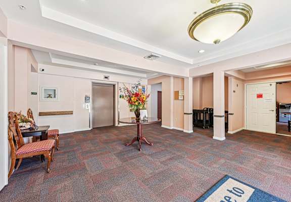 A hallway with a carpeted floor and a blue mat that says "Please do not walk on".