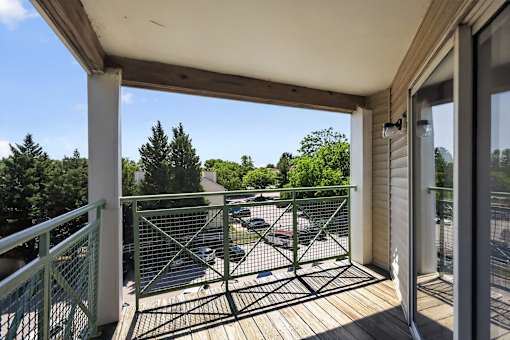 A balcony with a green railing overlooks a parking lot.