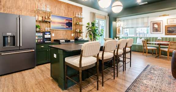 A kitchen with a refrigerator, chairs, and a table.