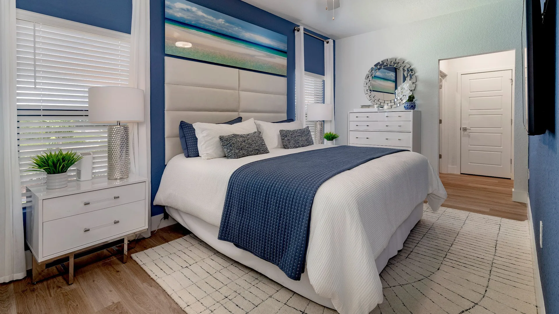 A modern bedroom featuring a blue and white color scheme with beach-themed decor.