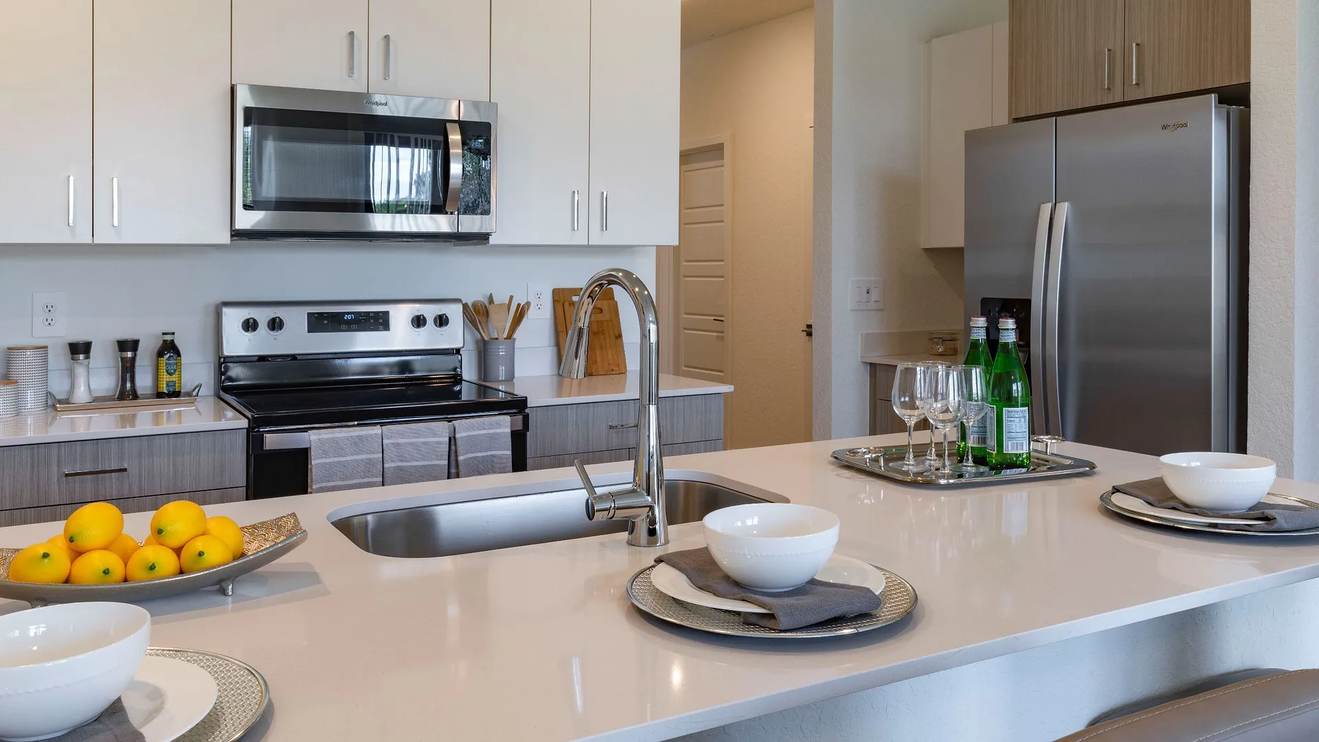 A modern kitchen featuring a sleek counter, stainless appliances, and a dining setup with bowls and a fruit bowl.