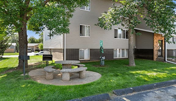 A tree stands in front of a grey building.