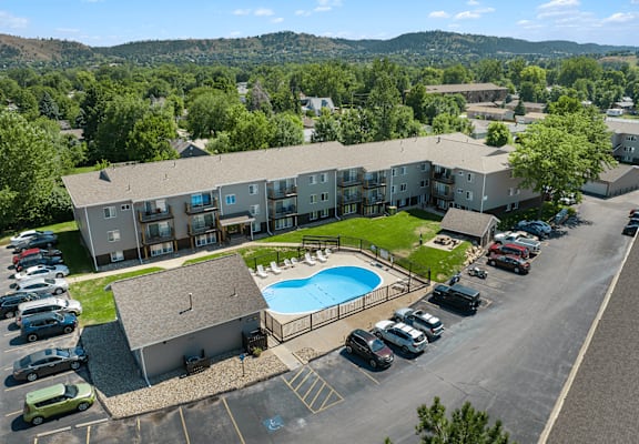 A large apartment complex with a swimming pool and a parking lot.