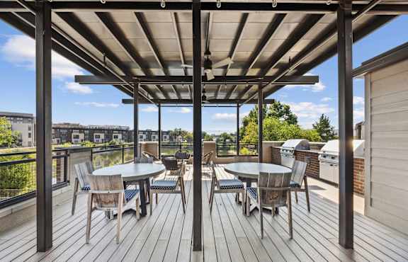 A wooden deck with a table and chairs under a roof.